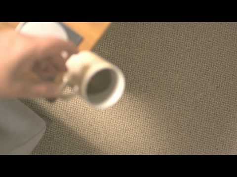 Hand holding a mug above light beige carpet.