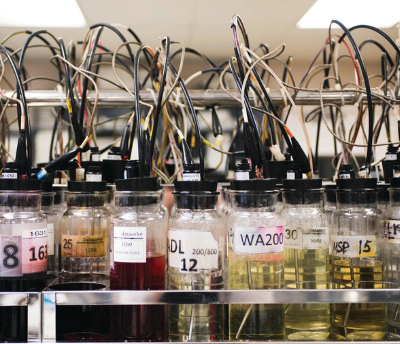 Lab bottles with liquids and wired testing equipment.