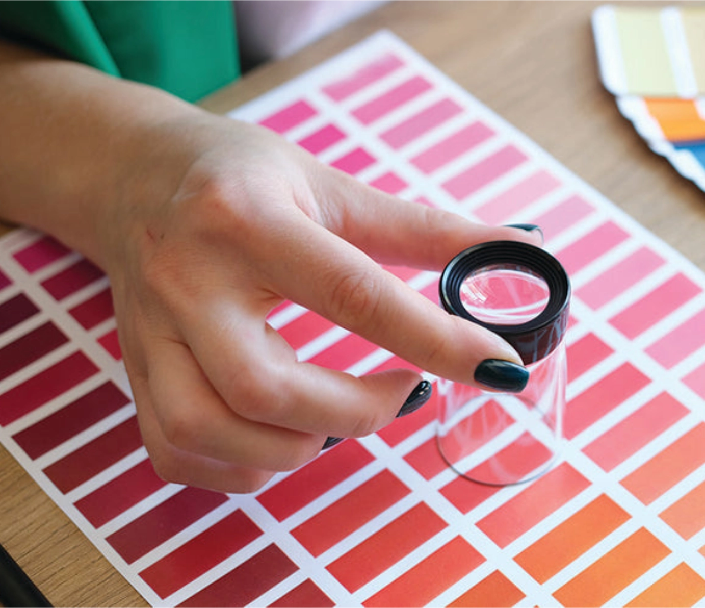 Hand using a loupe magnifier over color swatch samples.